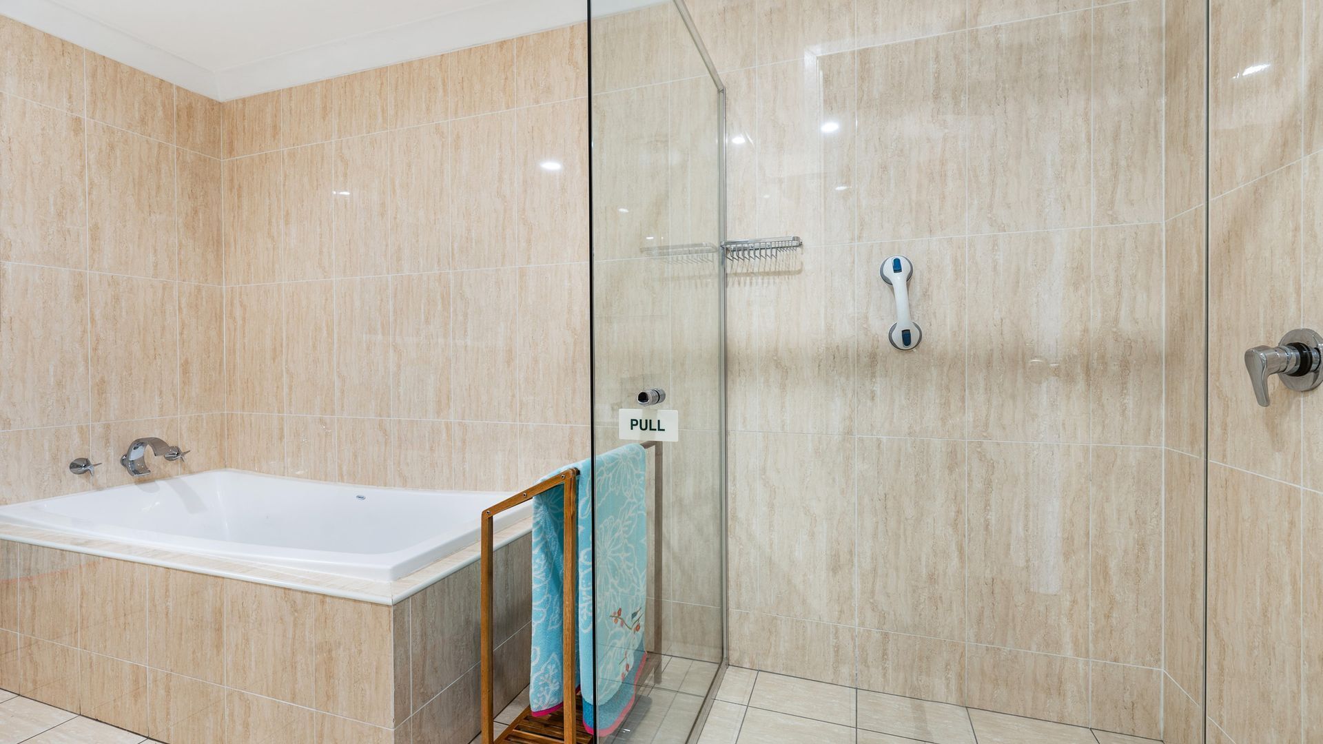 Une salle de bain moderne avec une douche à parois de verre, une baignoire blanche et un porte-serviettes avec une serviette.