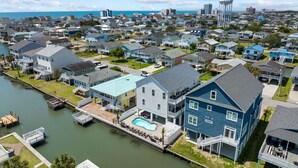 Un quartier résidentiel bordé de maisons donnant sur le front de mer, où l’on trouve notamment une grande maison avec une vaste terrasse avant et une piscine.