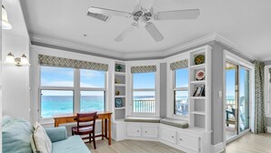 Une chambre avec vue sur l’océan, un ventilateur de plafond, un bureau et un canapé bleu.