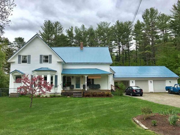 Une maison à deux étages avec un toit bleu, un porche à l’avant et un garage.