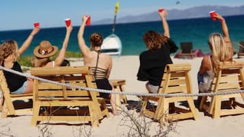A beach with wooden chairs and a rope barrier.