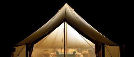 Een tent met een puntige top en een helder zicht op een bed van binnen.