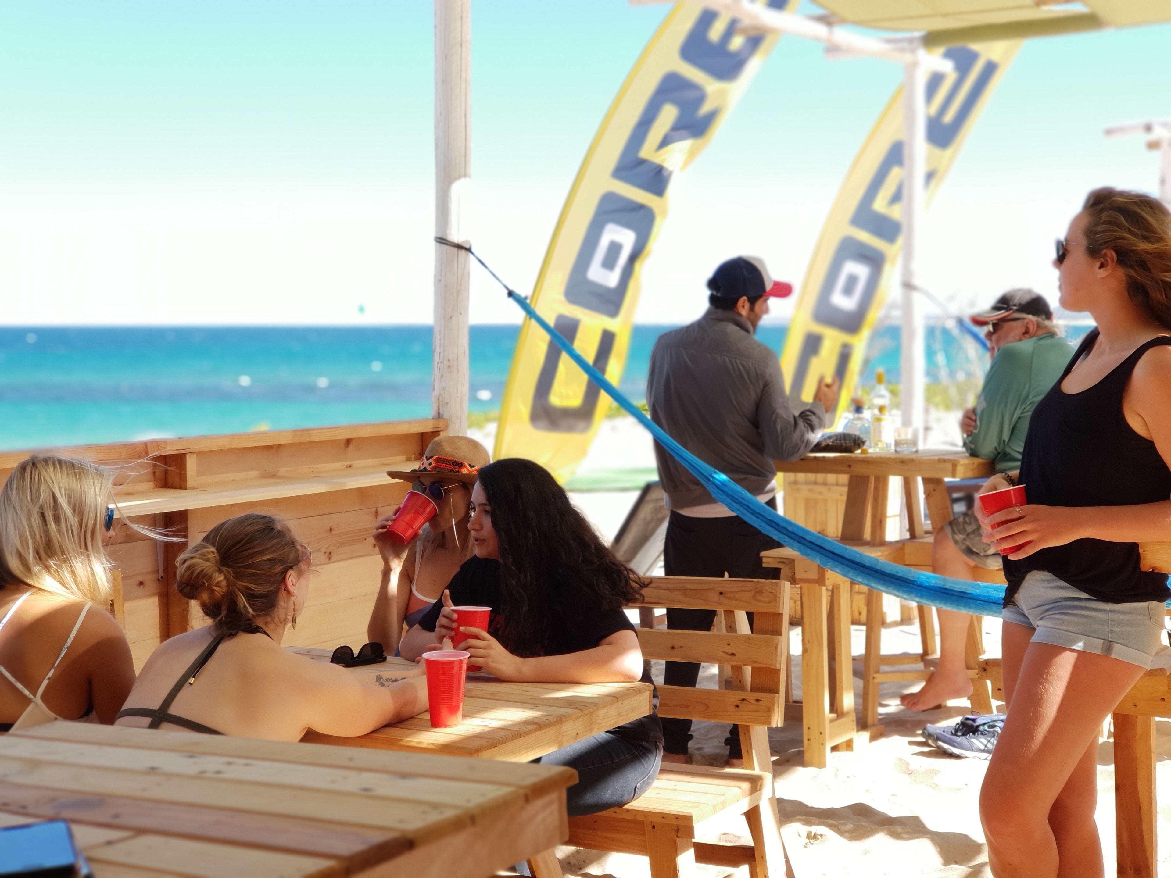 A beachside café with wooden tables and benches, overlooking the ocean.