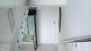 A wooden staircase with a glass railing on the left and a white wall on the right.