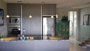 A modern kitchen with stainless steel appliances, a marble countertop, and pendant lighting.