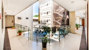 Amplio espacio interior con barandilla de cristal que da a un estacionamiento y un edificio de varios pisos.