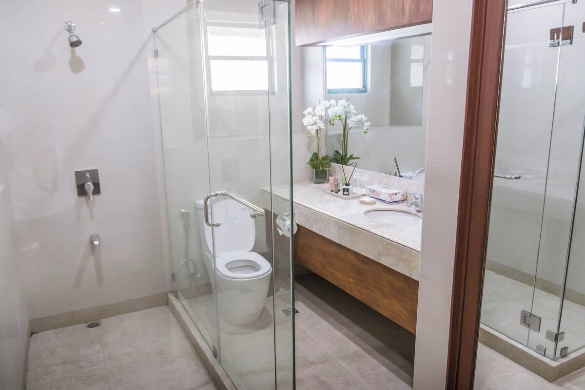 A modern bathroom with a glass-enclosed shower, a toilet, a vanity with a mirror, and a sink.