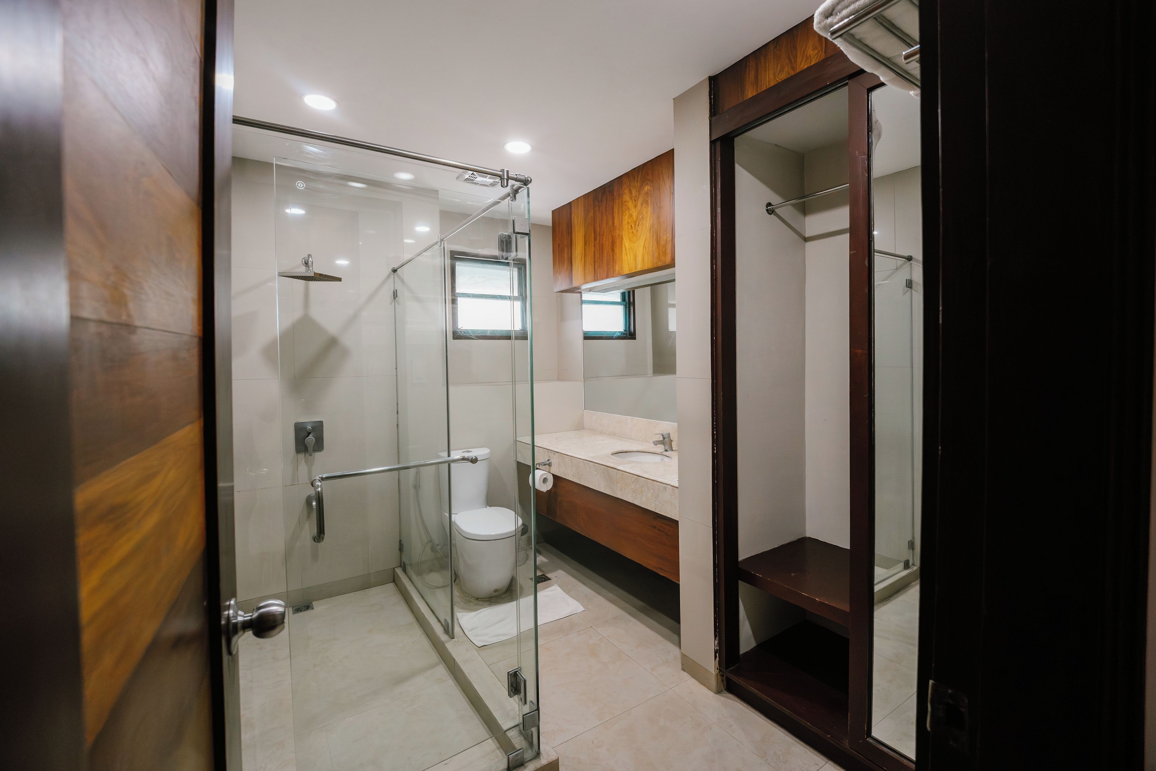 Un baño moderno con ducha envuelta en vidrio, inodoro y tocador con espejo.