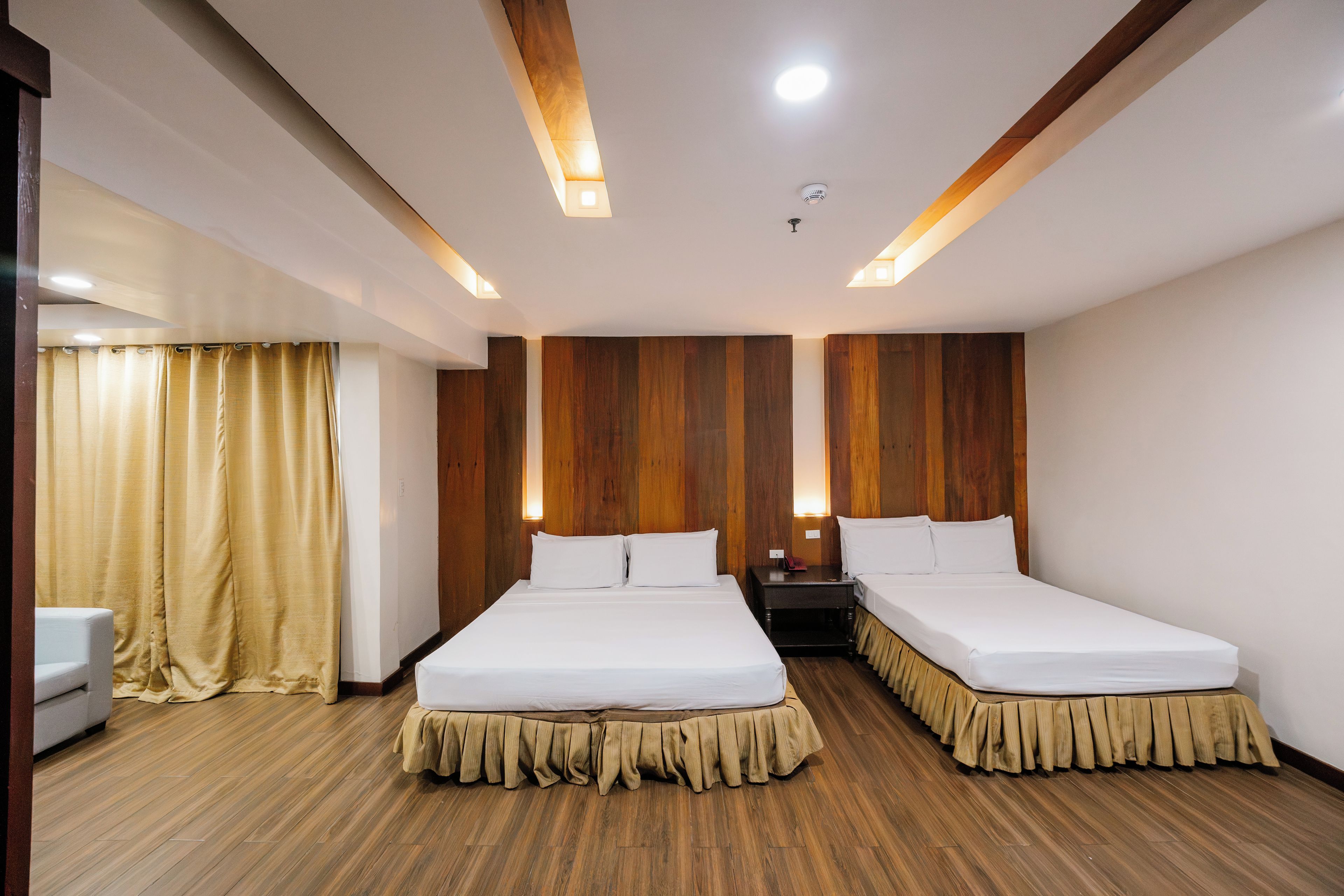 A hotel room with two beds, wooden panel walls, and a wooden floor.