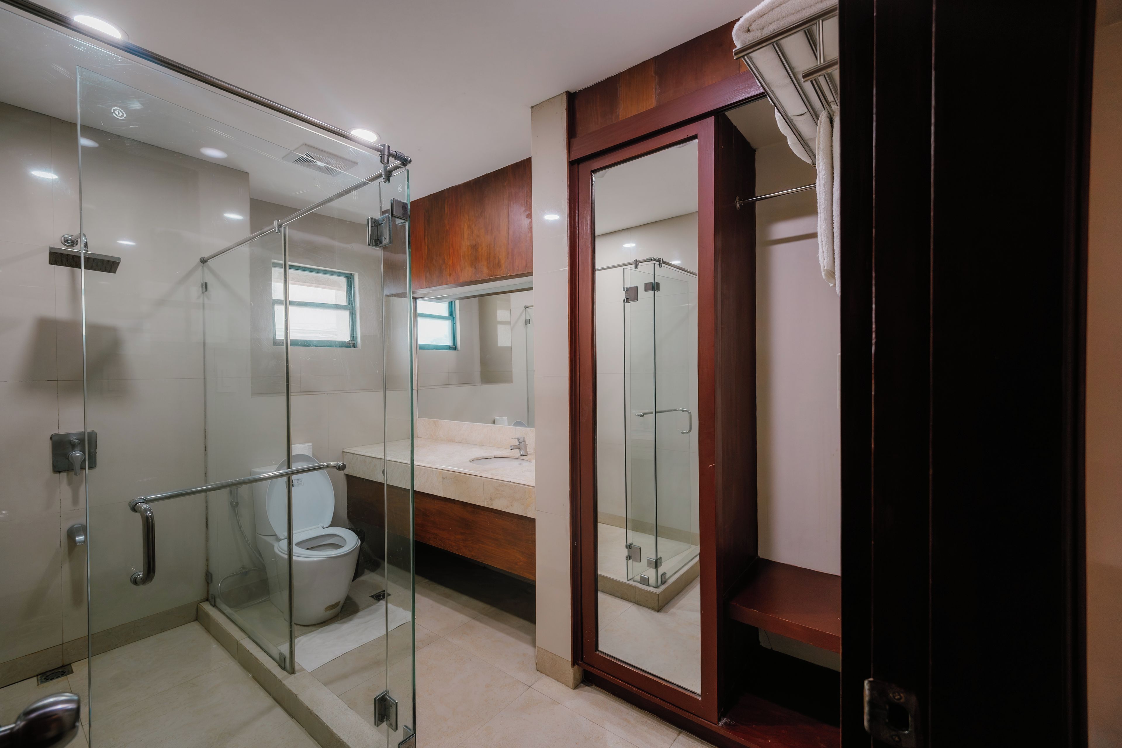 A modern bathroom with a glass-enclosed shower, a toilet, and a vanity with a mirror.