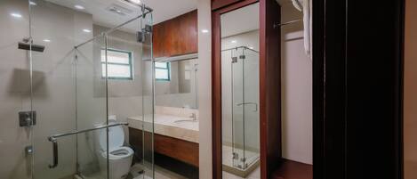 A modern bathroom with a glass-enclosed shower, a toilet, and a vanity with a mirror.