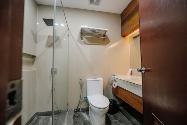 A bathroom with a glass-enclosed shower, a toilet, and a sink with a towel rack above it.