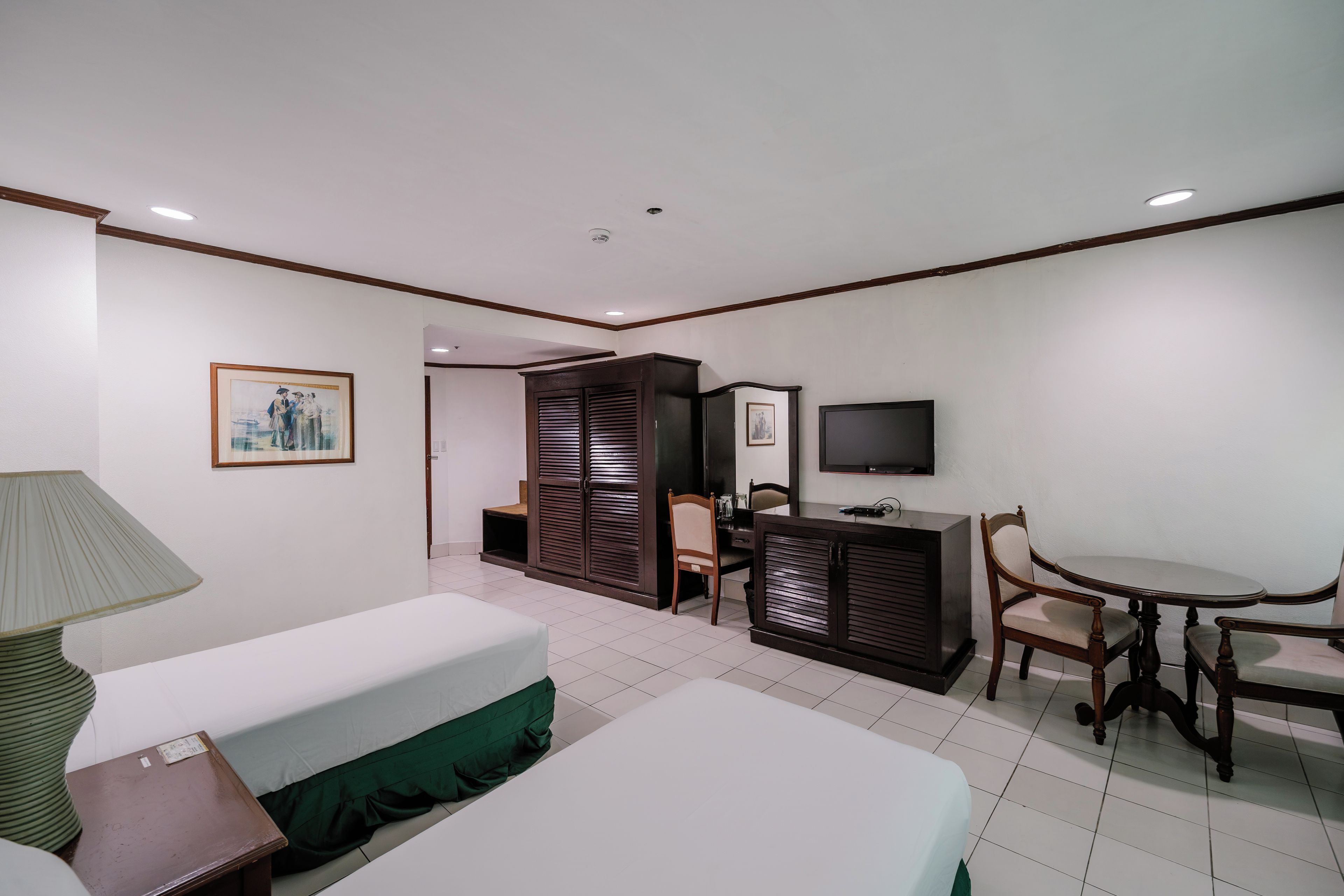 Ein Hotelzimmer mit Bett, Schreibtisch, Stuhl, Fernseher und Lampe.
