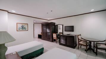 Ein Hotelzimmer mit Bett, Schreibtisch, Stuhl, Fernseher und Lampe.