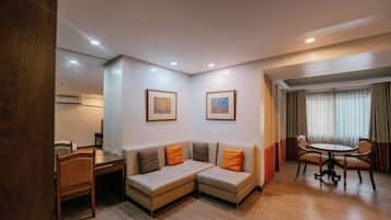 Una habitación de hotel con un sofá, una mesa de comedor y dos cuadros en la pared.