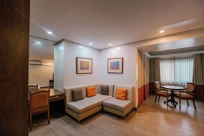 A hotel room with a sofa, a dining table, and two framed pictures on the wall. - La Fiesta Hotel (Iloilo)