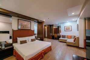 Ein Hotelzimmer mit einem großen Bett, einer Couch, einem Schreibtisch und einem Fernseher.