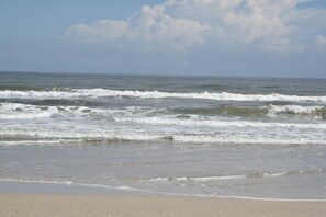 A beach with waves and a clear sky.