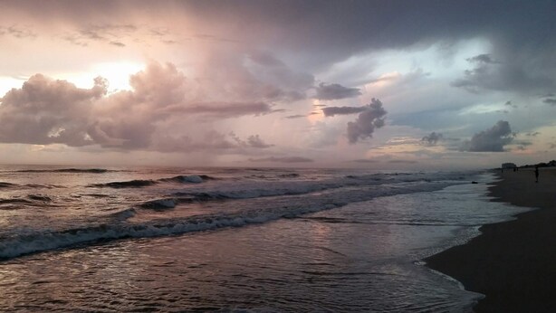 A beach with waves and a cloudy sky.