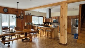 Una cocina amplia con armarios de madera, una isla central y un comedor con mesa y sillas de madera.