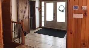 Una escalera de madera que lleva a una habitación con una puerta corredera, un felpudo y una corona en la puerta.
