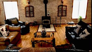 Una sala de estar acogedora con chimenea, sofás de cuero y una pared de piedra.