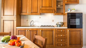Een keuken met houten kastjes, een spoelbak, een fornuis en een aanrecht met groenten.