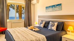 Een slaapkamer met een groot bed, uitzicht op zee en een schilderij aan de muur.