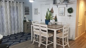 A dining area with a wooden table and chairs, a potted plant, and decorative wall art. - Lake front with dock and Beautiful view  (Afton)