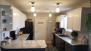 A kitchen with white cabinets, a marble countertop, a refrigerator, a sink, and a door labeled "laundry". - Lake front with dock and Beautiful view  (Afton)