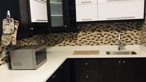 Een moderne keuken met zwart-wit kasten, een magnetron, een spoelbak en een klok aan de muur.