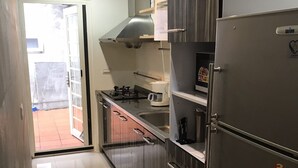 Una cocina con un refrigerador de acero inoxidable, una estufa a gas y una cafetera.