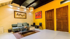 Una sala de estar moderna con un sofá, una mesa de centro y sillas. Hay dos puertas y una obra de arte enmarcada en la pared.