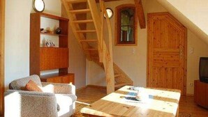 Una sala acogedora con una escalera de madera, un sofá, una mesa de centro y un televisor.