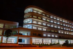 Un hotel de varios pisos con balcones, ventanas amplias y una entrada bien iluminada.