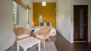 A bedroom with a bed, two wicker chairs, a nightstand, and a bedside table. - Just Like Villa (Ji'an)