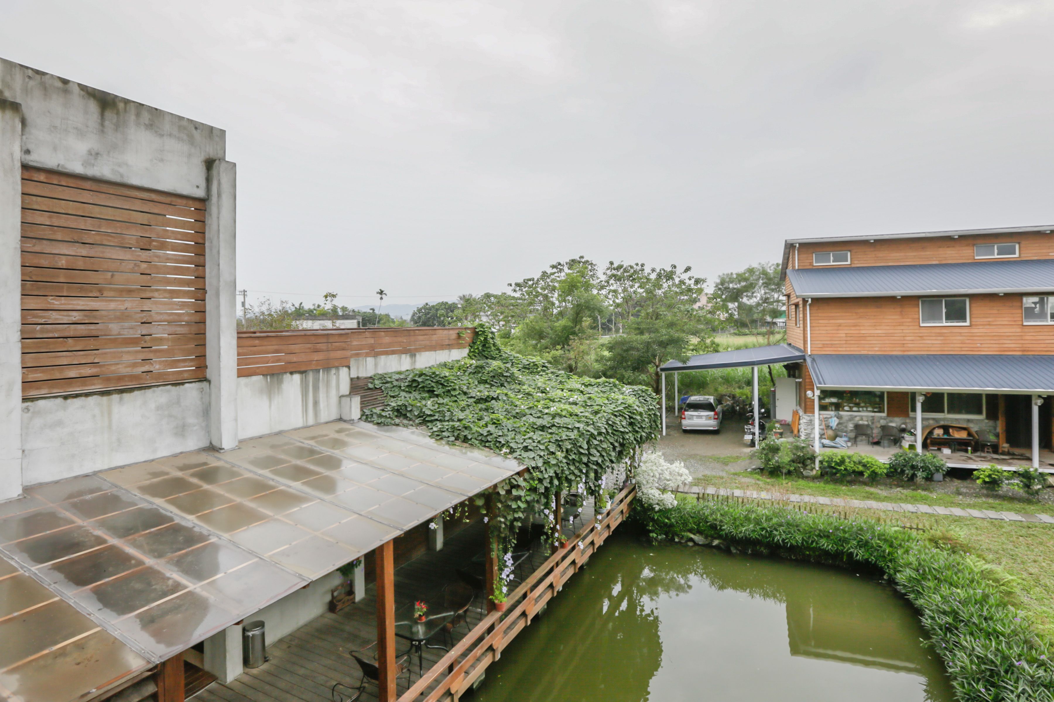 A modern building with a covered outdoor seating area and a small pond.