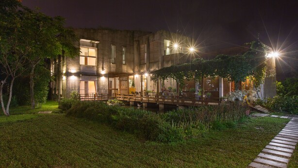 A modern building with multiple illuminated windows and a wooden deck. - Just Like Villa (Ji'an)
