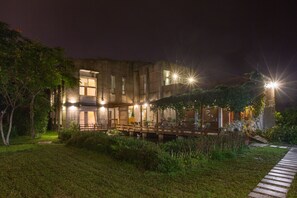 A modern building with multiple illuminated windows and a wooden deck. - Just Like Villa (Ji'an)