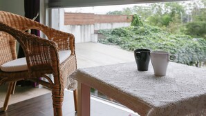 A wicker chair with a cushion, a table with a lace tablecloth, and two mugs on the table. - Just Like Villa (Ji'an)