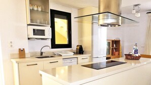 A modern kitchen with a central island, a microwave, a dishwasher, and a stainless steel range hood.