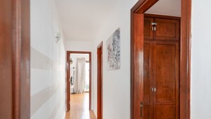 A hallway with wooden doors, a white wall, and a door with a 'HOME' sign. - Charming "La Florida" Apartment with Pool, Balcony, Sea Views & Wi-Fi (Tías)