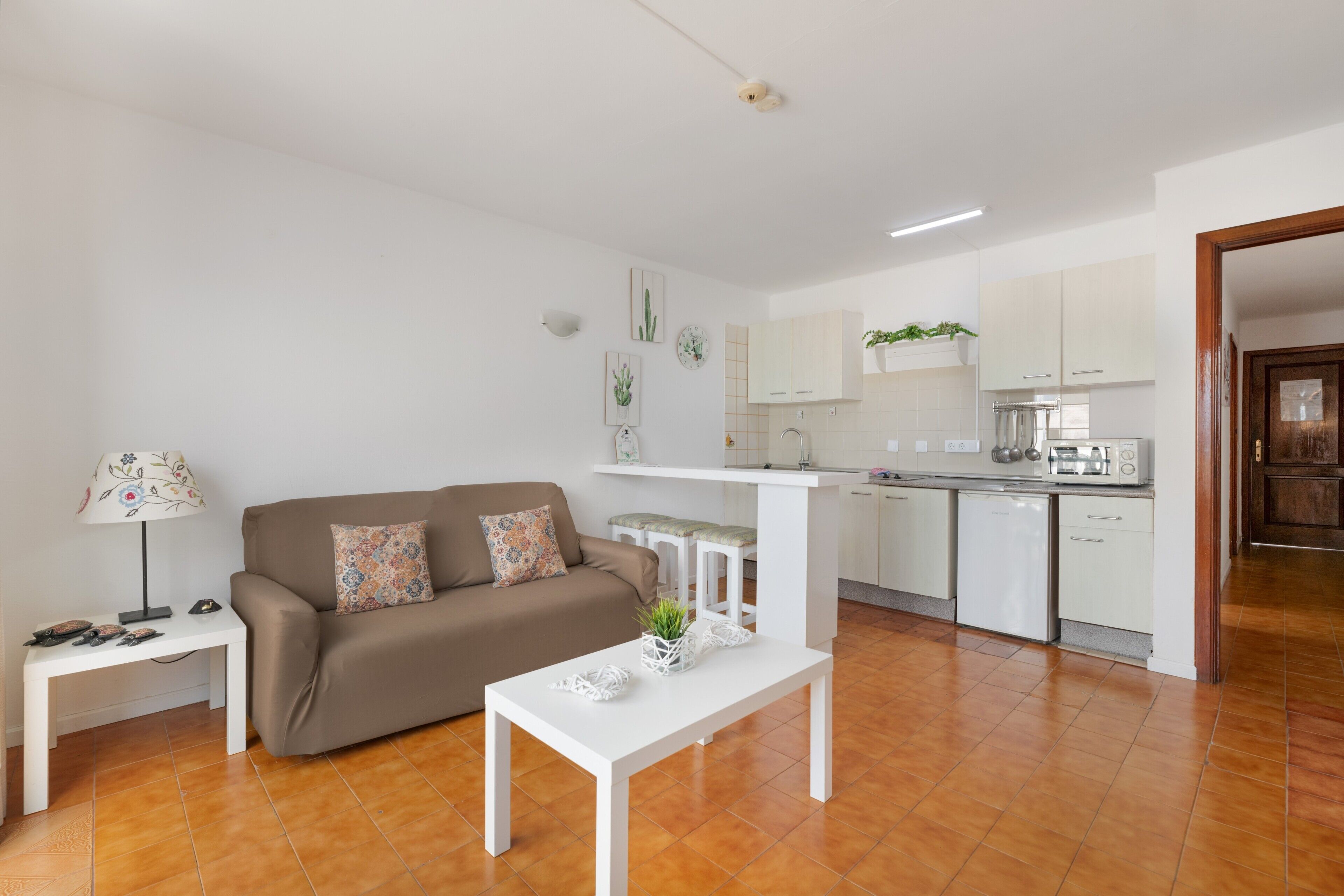 Ein modernes Wohnzimmer mit einer Couch, einem Couchtisch und einer kleinen Küche im Hintergrund.