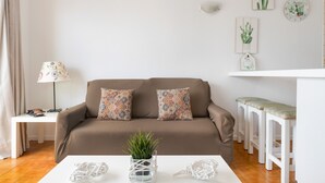 A living room with a brown sofa, patterned cushions, a white coffee table, and a small plant. - Charming "La Florida" Apartment with Pool, Balcony, Sea Views & Wi-Fi (Tías)