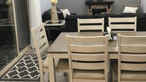 A dining area with a table and chairs, a sofa, a TV, and a ceiling fan.