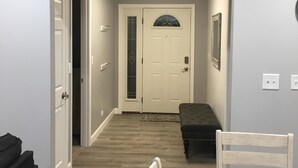 A room with a dining table, chairs, a bench, a door with a glass panel, and a ceiling fan.
