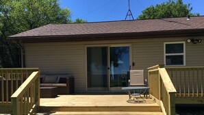 A house with a wooden deck, a sliding glass door, a small patio table, and a chair.