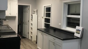 A kitchen with white cabinets, a black countertop, and a window with a view.