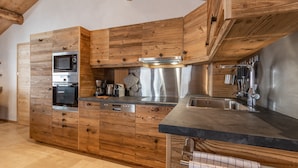 A modern kitchen with wooden cabinetry, stainless steel appliances, and a black countertop.