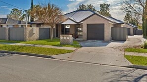 A residential house with a garage, a driveway, and a well-maintained lawn. - Tranquil Pet friendly, close to the airport, free NBN and Netflix! (East Albury)